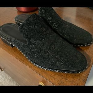 Black Adrianna Papell mules with a slight heel and subtle floral embellishments